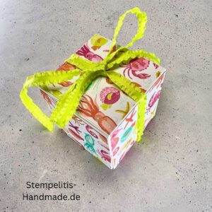 Handdekorierte Geschenkschachtel mit Schleife von oben, Geschenkschachtel mit liebevollem Aufkleber “Mit viel Liebe verschenkt”, Detailansicht Schleife auf Geschenkschachtel, Seitenansicht Geschenkschachtel mit buntem Designpapier, Offene Geschenkbox zum Befüllen, Geschenkschachtel auf hellem Hintergrund mit Dekorband, Handgemachte Geschenkverpackung mit grünem Band und Etikett